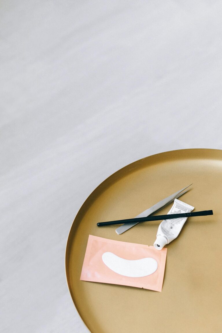 Minimalist flat lay of skincare tools and eye mask on round golden tray, ideal for beauty and wellness concepts.